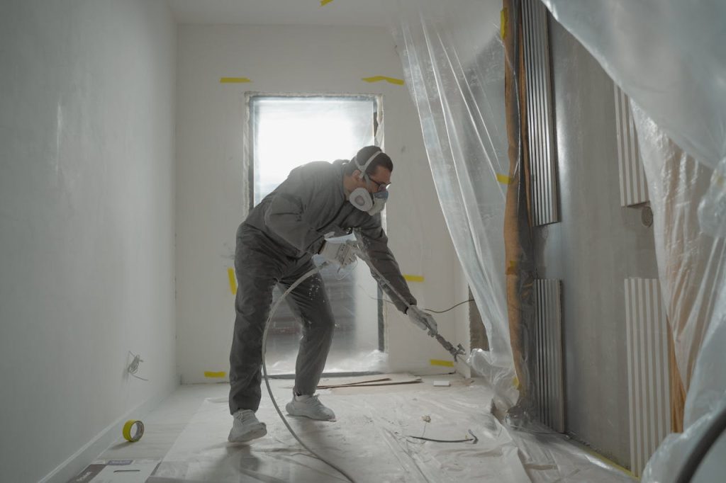 man-in-black-jacket-and-black-pants-wearing-white-helmet-6474300 A worker in protective gear painting walls during an indoor renovation project.